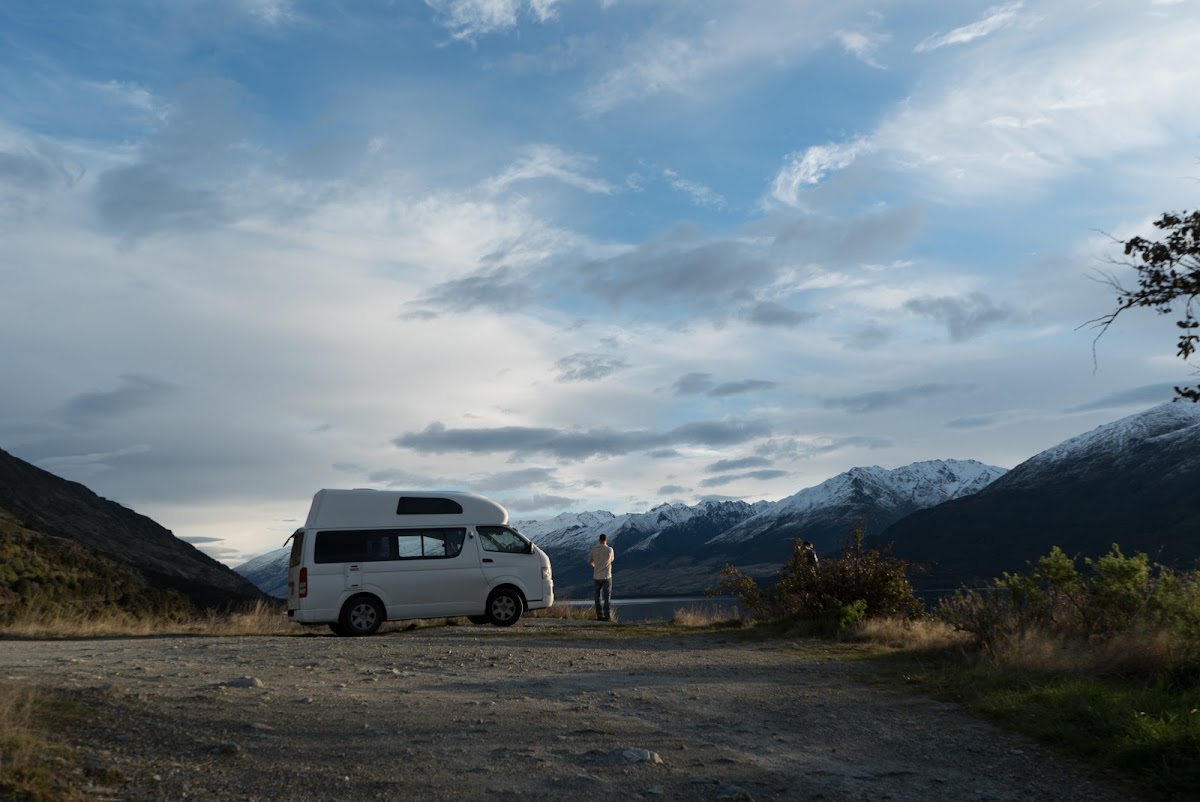 Campervan parked by a lake with mountains behind