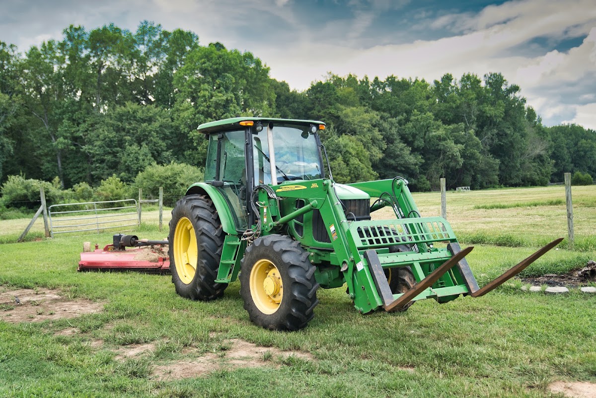Green tractor with a front-end loader in a paddock